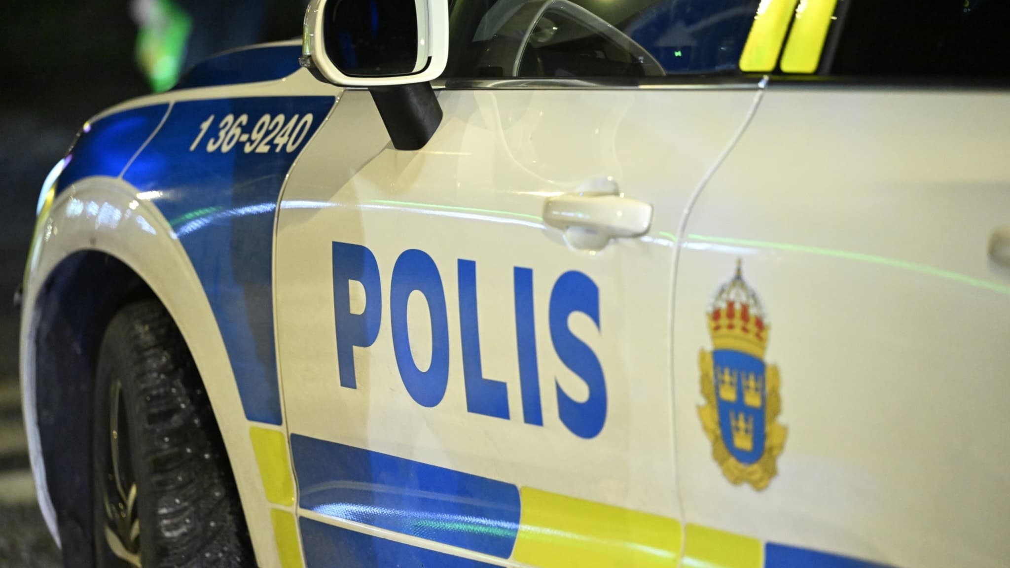En polisbil är parkerad vid en brottsplats. Det är mörkt på platsen. 