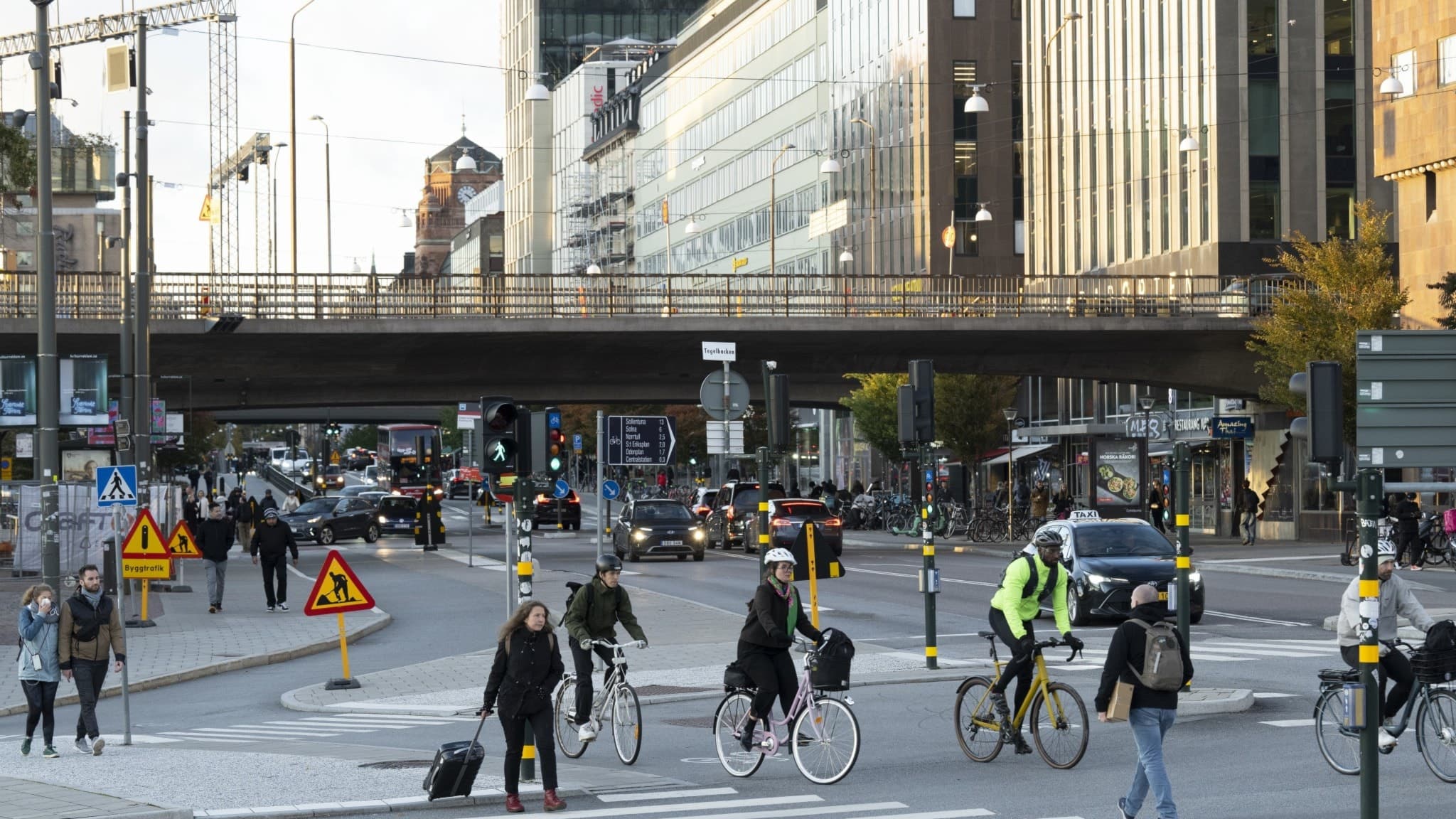 Centralt gatukors i stadsmiljö med cyklister och fotgängare i rörelse.