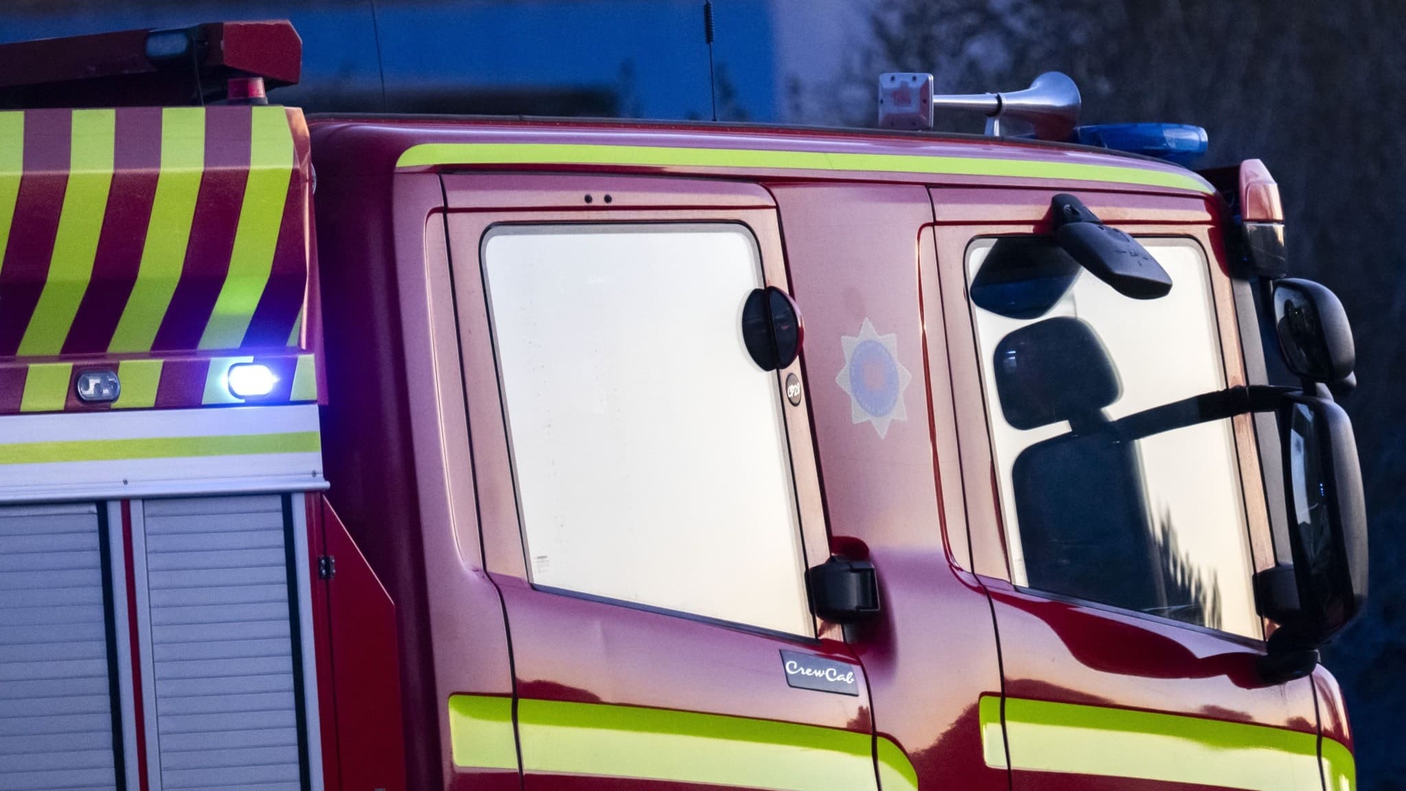 Brandbil från räddningstjänsten bekämpar en villabrand på Johan Klints väg i Sölvesborg. Eld och rök syns i bakgrunden. Insatsen pågår under kvällstid.