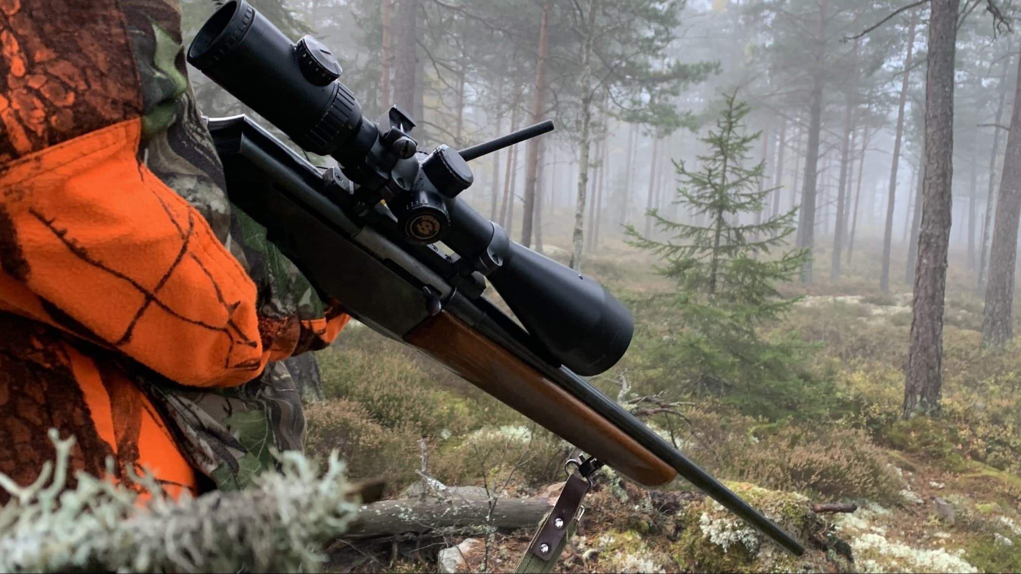 Ett jaktgevär hålls av en jägare ute i dimmig skog