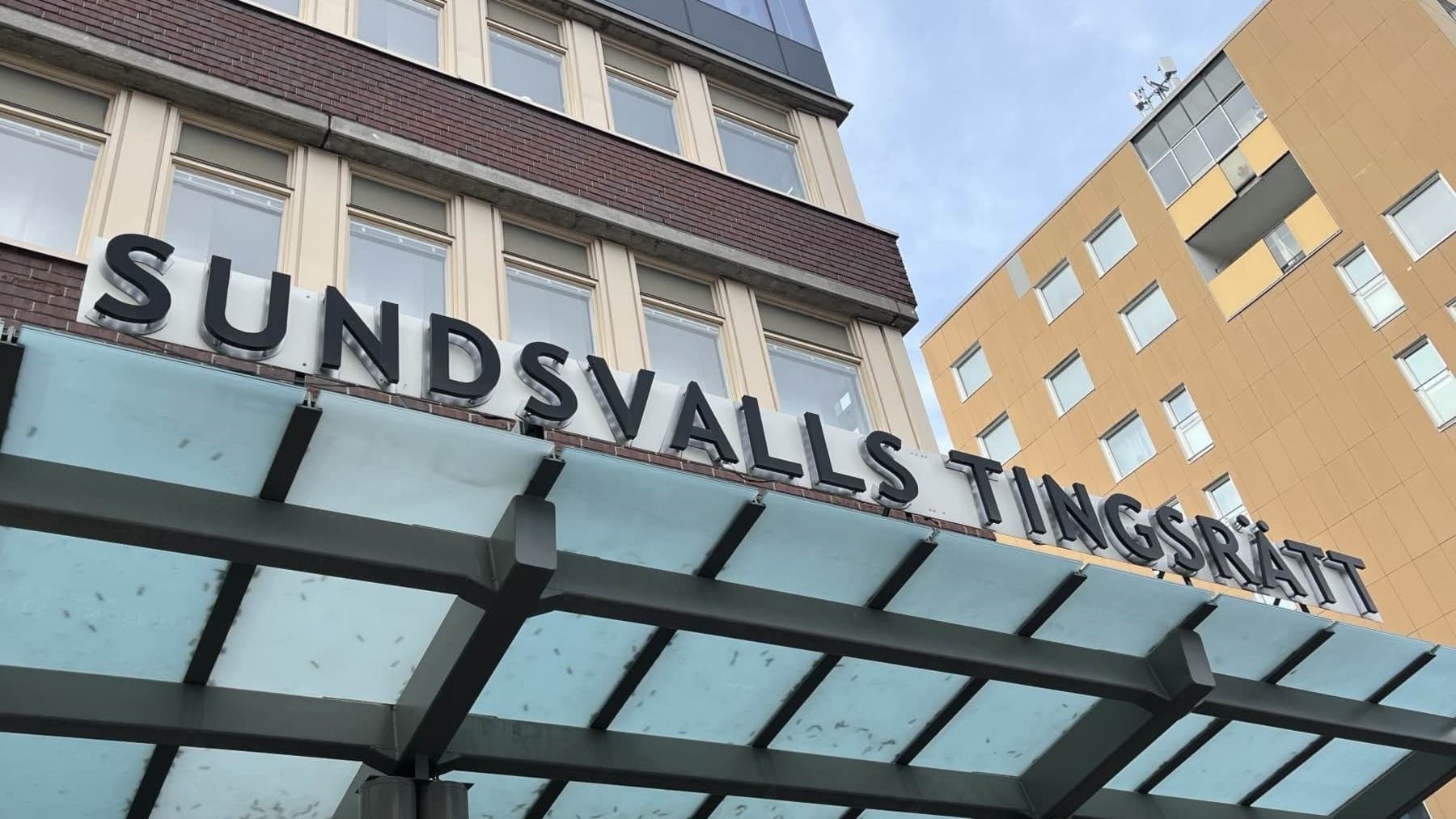 Bild på exteriören av Sundsvalls tingsrätt. Två byggnadsfasader tar upp det mesta av utrymmet i bilden, utöver skylten för tingsrätten.