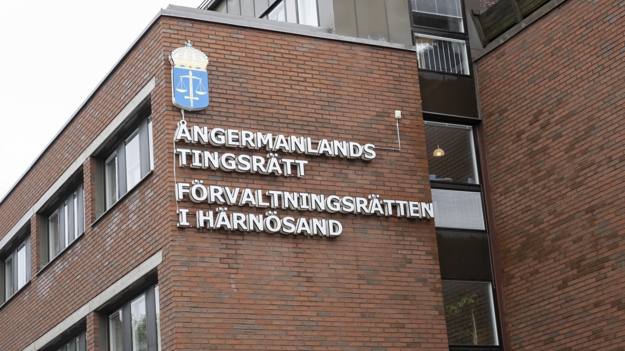 Ångermanlands tingsrätts byggnad i Härnösand med fasad i rödbrunt tegel och texten 'Ångermanlands tingsrätt Förvaltningsrätten i Härnösand' tydligt synlig på väggen.