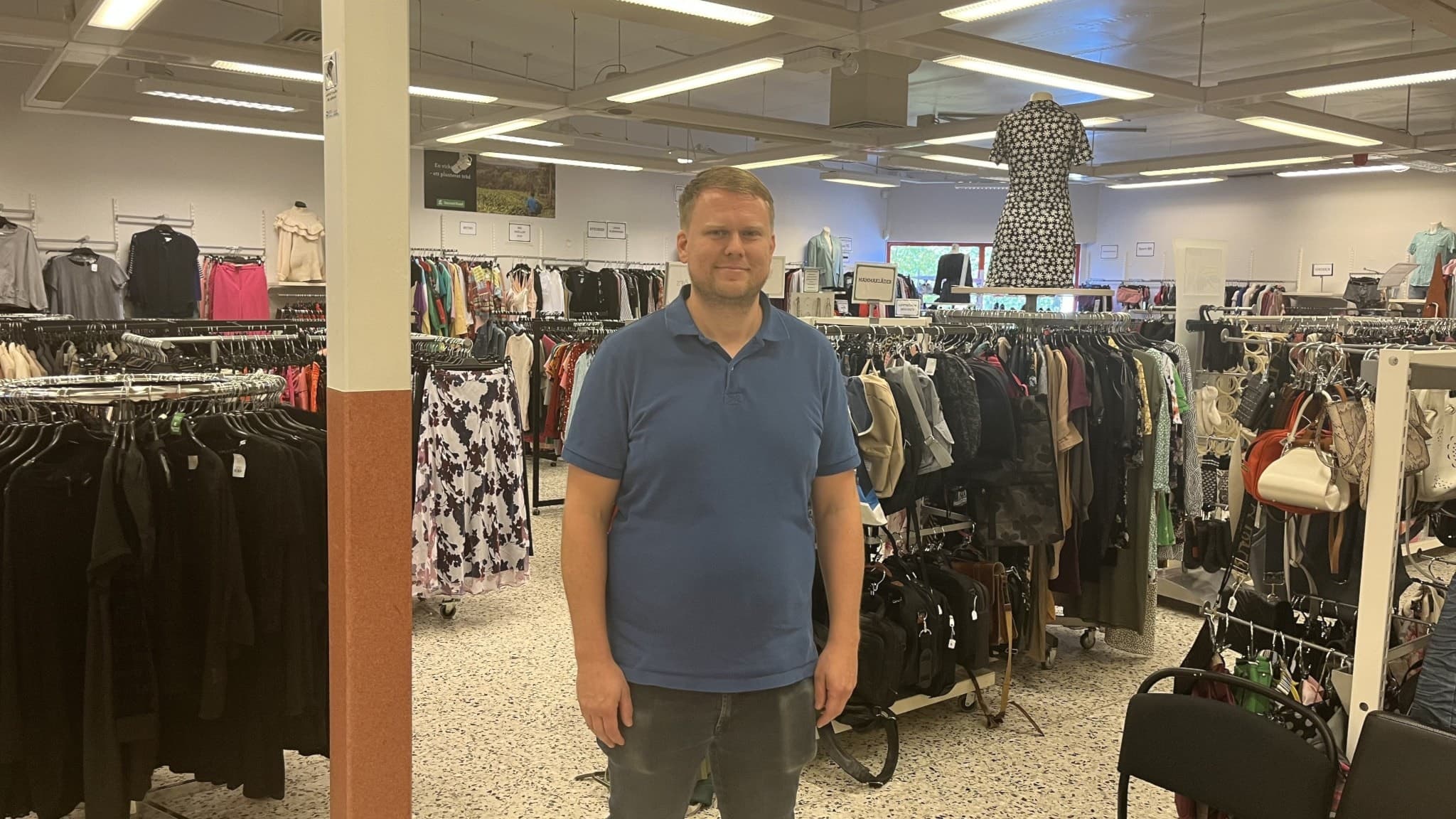 Andreas Jacobsson, verksamhetsföreståndare för PMU Second Hand i Örnsköldsvik, står i butikens lokaler omgiven av klädställningar och second hand-varor.