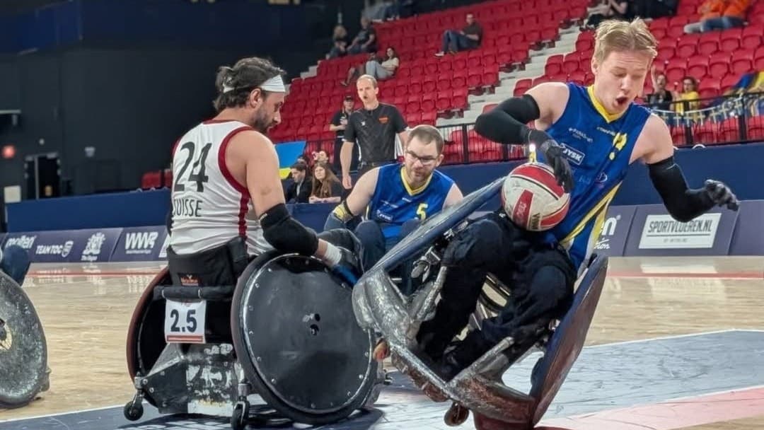 Edvard Nyholm, Rullstolsrugbyspelare i en intensiv match på en inomhusarena. En spelare i blått från Sverige kämpar om bollen mot en motståndare i vitt.