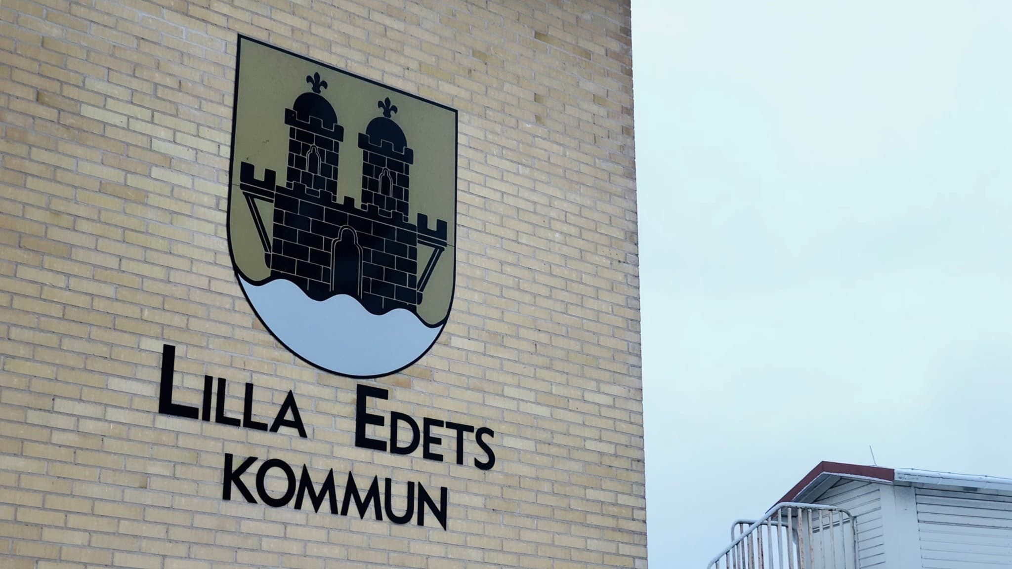 Lilla Edets kommunlogga avtecknad på kommunhuset i staden. En byggnad av beige tegel; rätt härlig ton. 