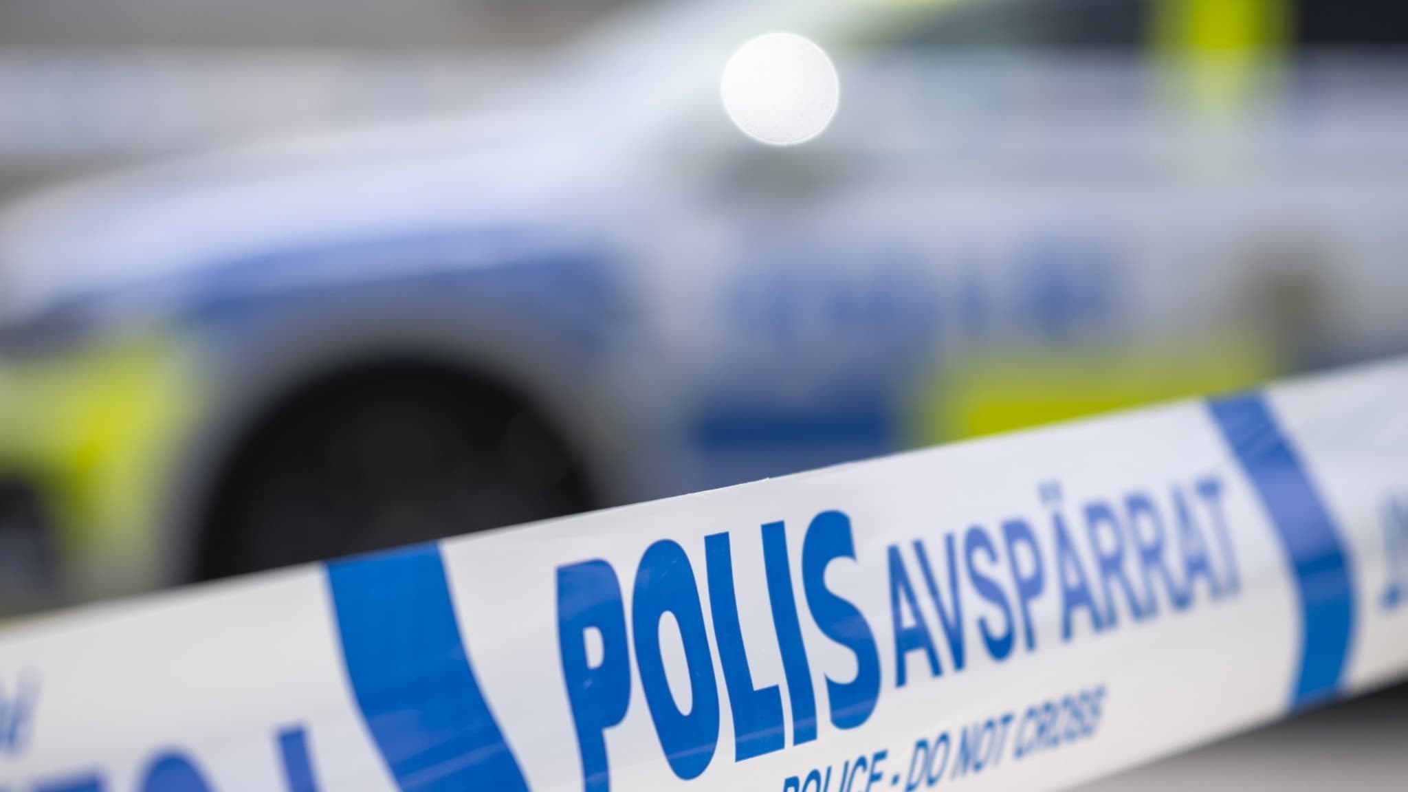 Polisens avspärrningsband med texten 'Polis – avspärrat' i förgrunden, bakom syns ett polisfordon suddigt. Bilden är från en misstänkt mordbrand i Bunkeflostrand utanför Malmö.