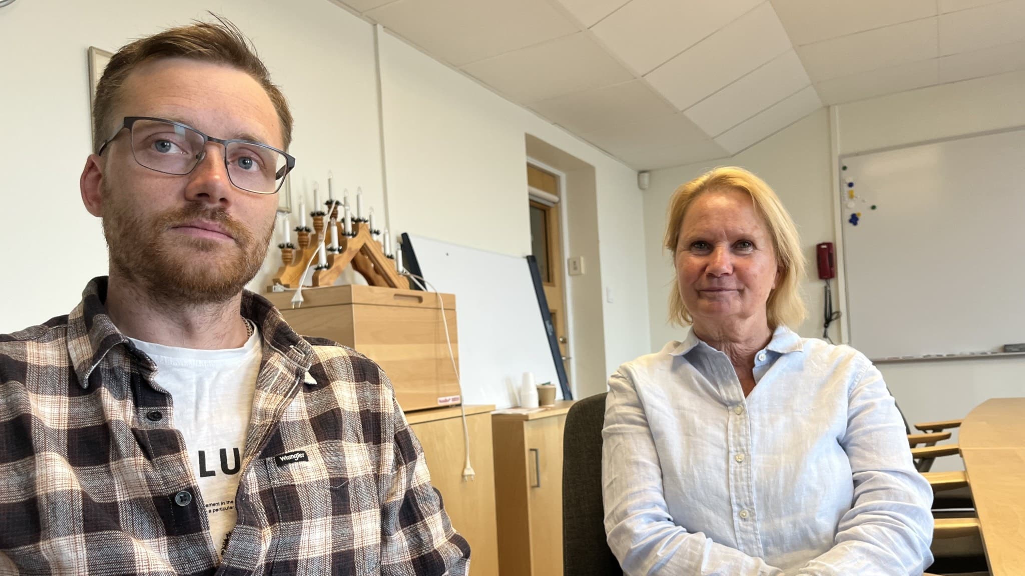 Stefan Appel och Marie-Louise Forsberg Fransson sitter i ett kontorsrum i Degerfors kommun, omgivna av skrivbord, hyllor och en whiteboardtavla i bakgrunden.