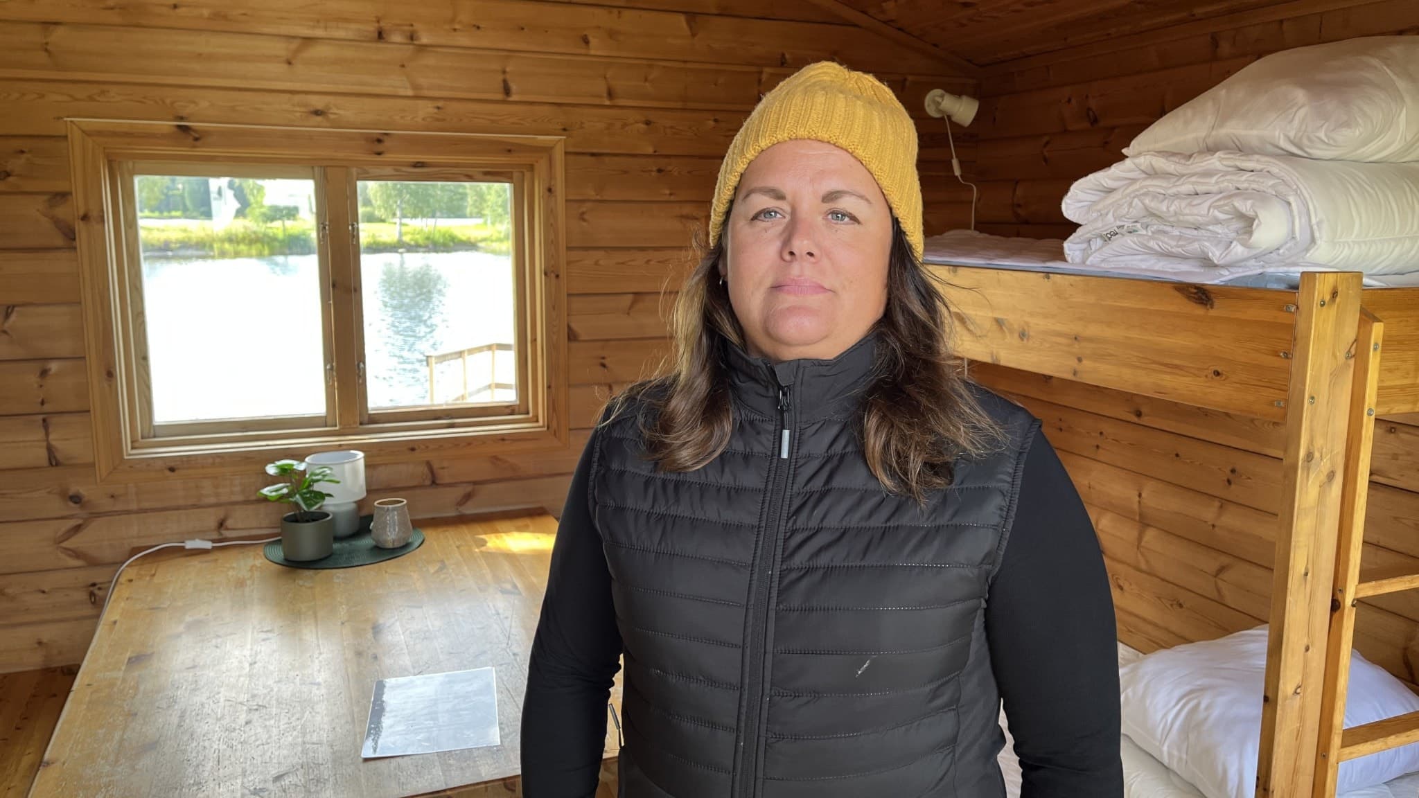 Kim Hedin, ordförande i Krokom Dvärsätts IF, står inne i en campingstuga med träväggar, våningssängar och ett fönster som vetter mot sjöutsikt.