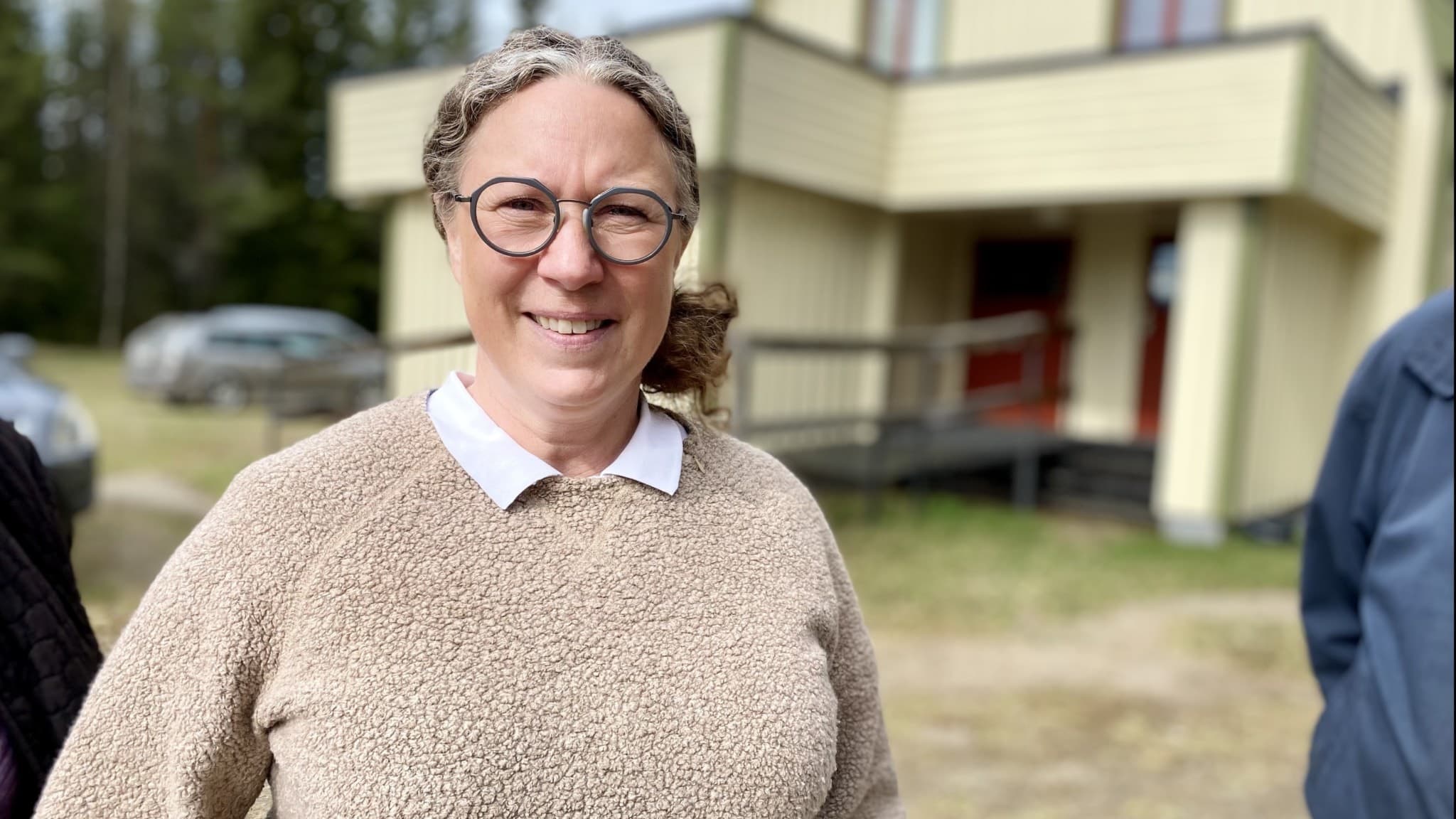 Kvinna i beige tröja framför bygdegård