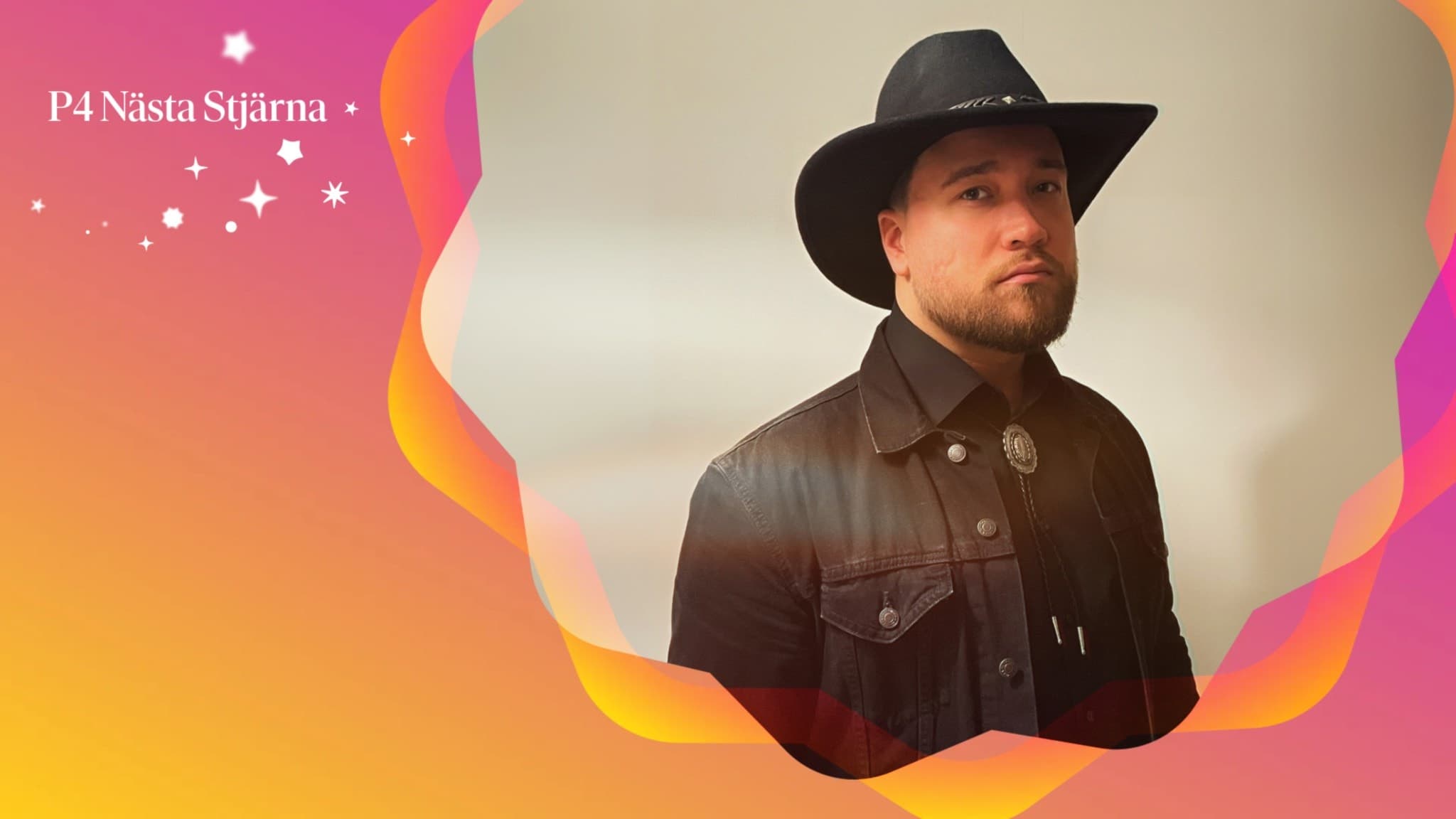 Alex Oakland, klädd i svart cowboyhatt och jacka, poserar framför en färgglad bakgrund med orangea och rosa toner. 