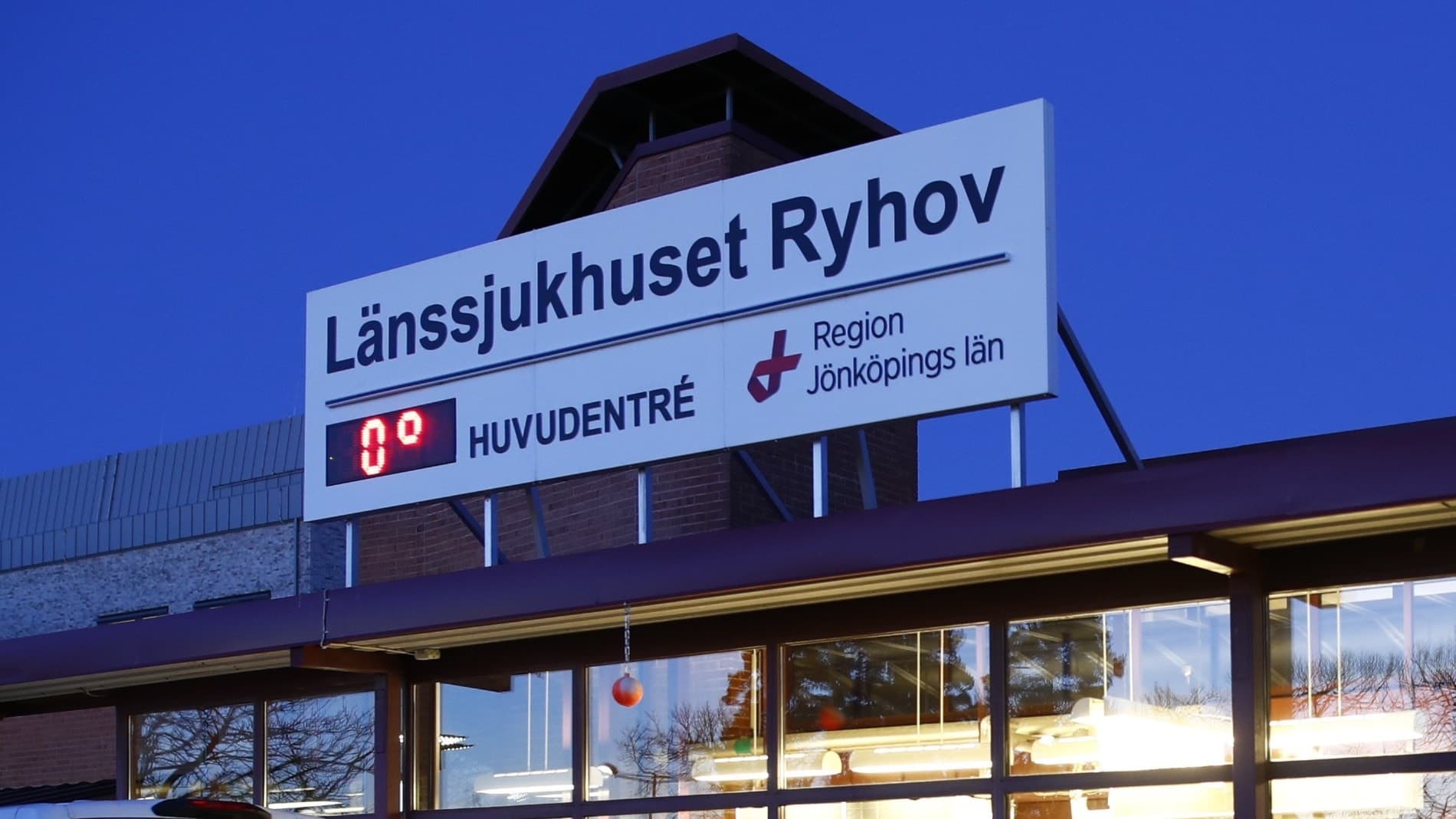 Entrén till Länssjukhuset Ryhov i Jönköping, upplyst i kvällsmörker. En vit minibuss står parkerad utanför. Sjukhuset är aktuellt efter en knivattack i Vetlanda där skadade vårdas.