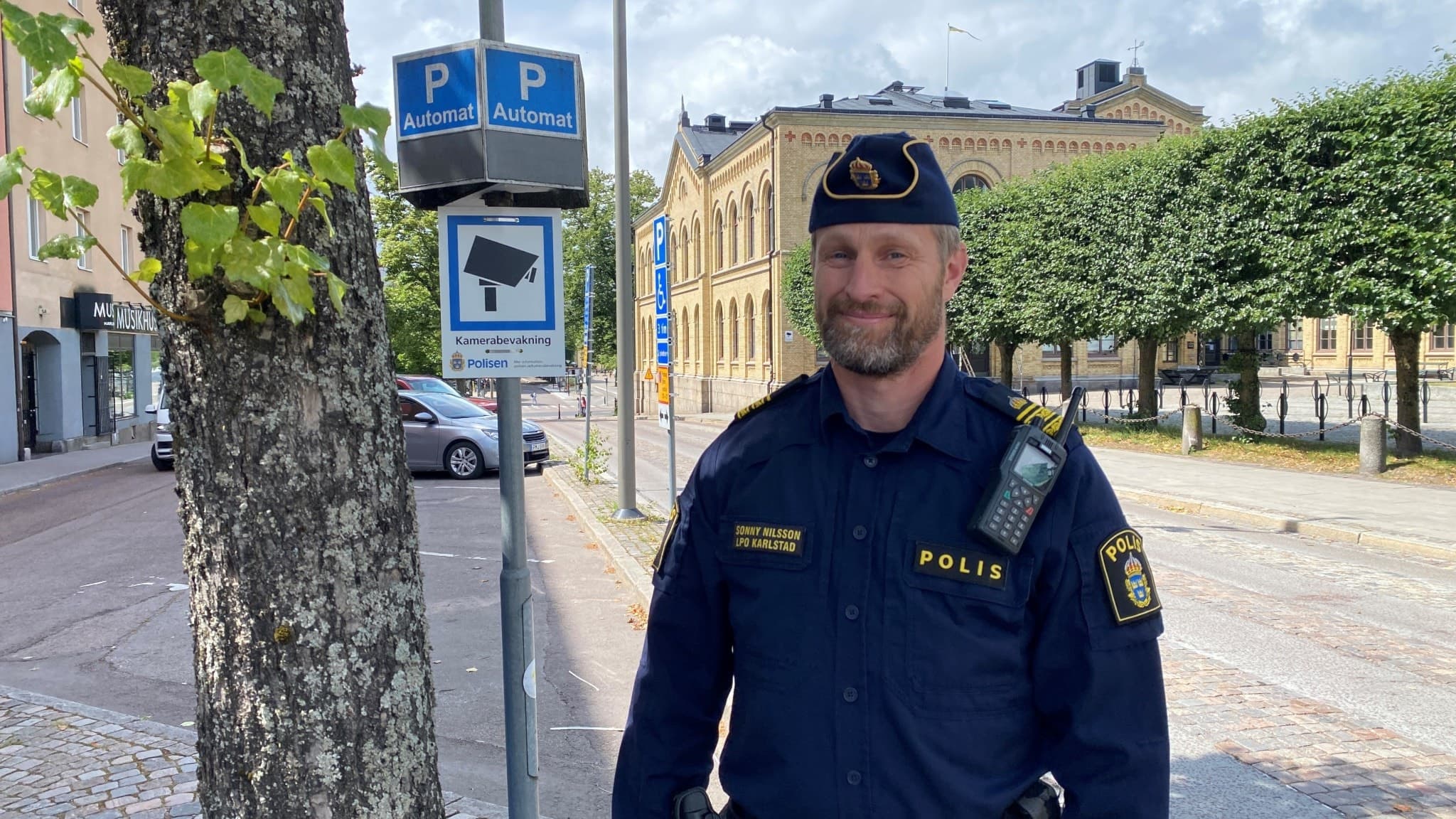 En man står bredvid skylten intill Stora Torget som informerar om att platsen övervakas med en kamera. 