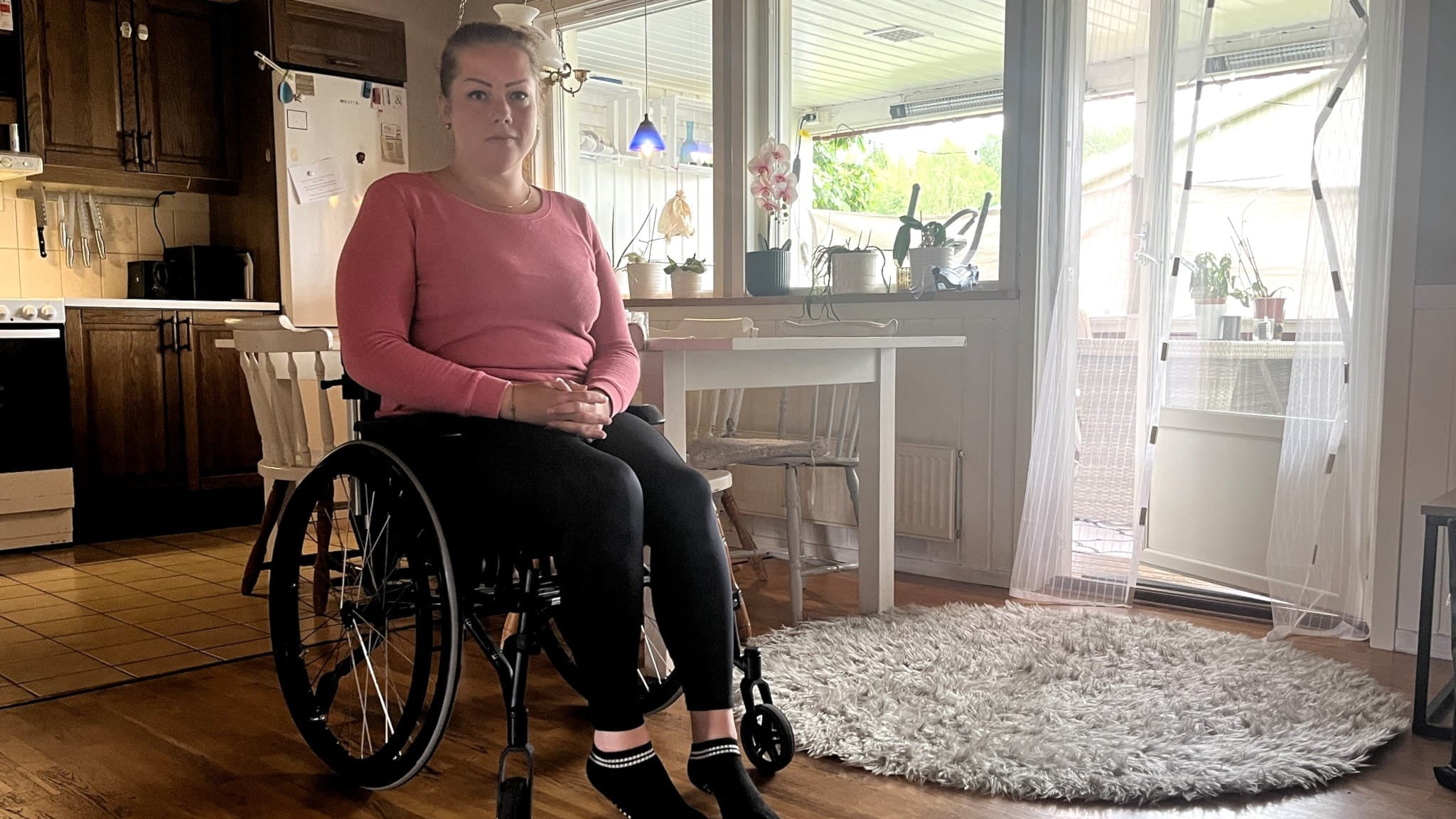 Angelica Henriksen sitter i rullstol i sitt kök efter en vårdskada. 