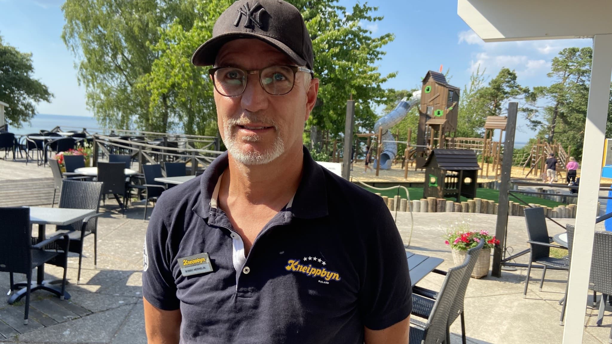 Bobbo Werkelin, avgående vd för Kneippbyn, står utomhus vid en uteservering med lekplats och grönska i bakgrunden. Han reflekterar över Gotlands vattenbrist och lösningar från Mallorca och Kanarieöarna.