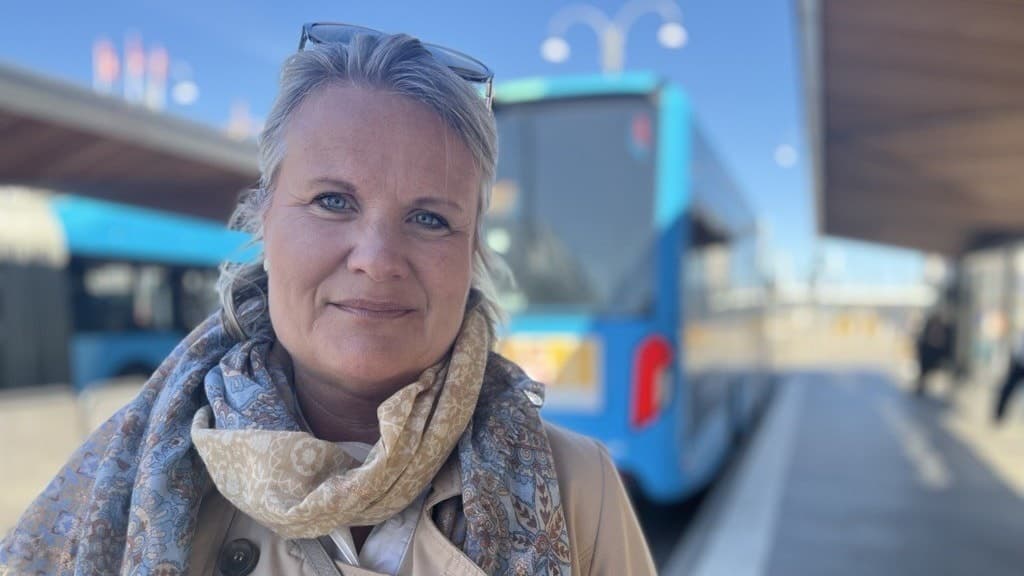 Kvinna som står utomhus. I bakgrunden är en blå buss. 