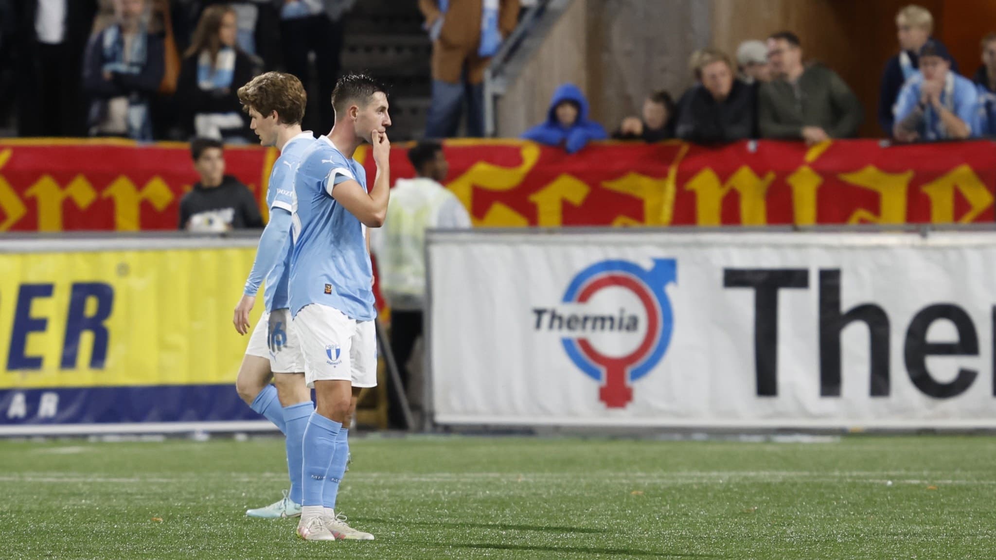 Lasse Berg Johnsson från Malmö FF ser deppig ut på planen under bortamatchen mot IK Sirius på Studenternas IP i Uppsala, med reklamskyltar och publik i bakgrunden.