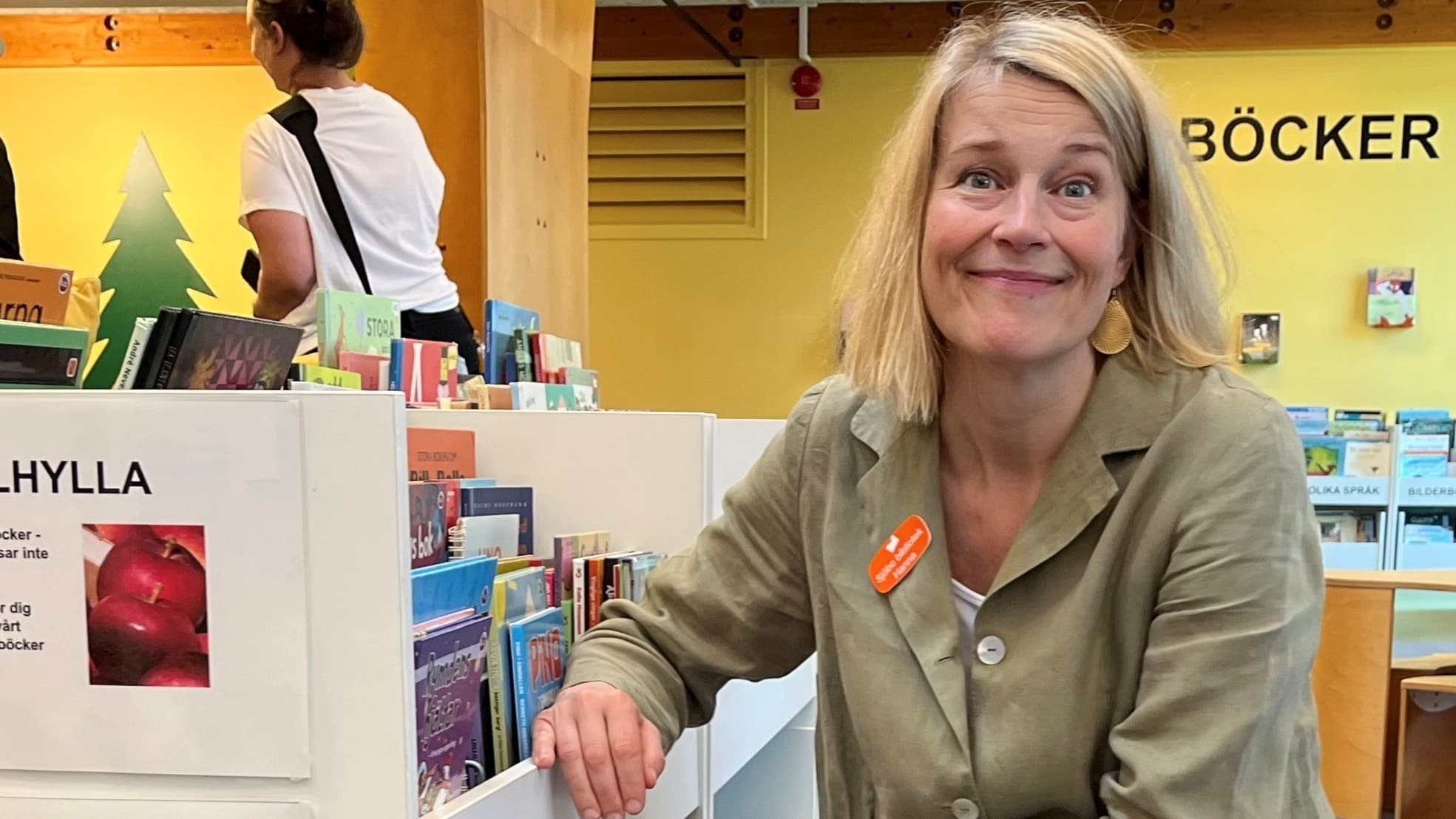 Kvinna i grön klänning bredvid en bokhylla