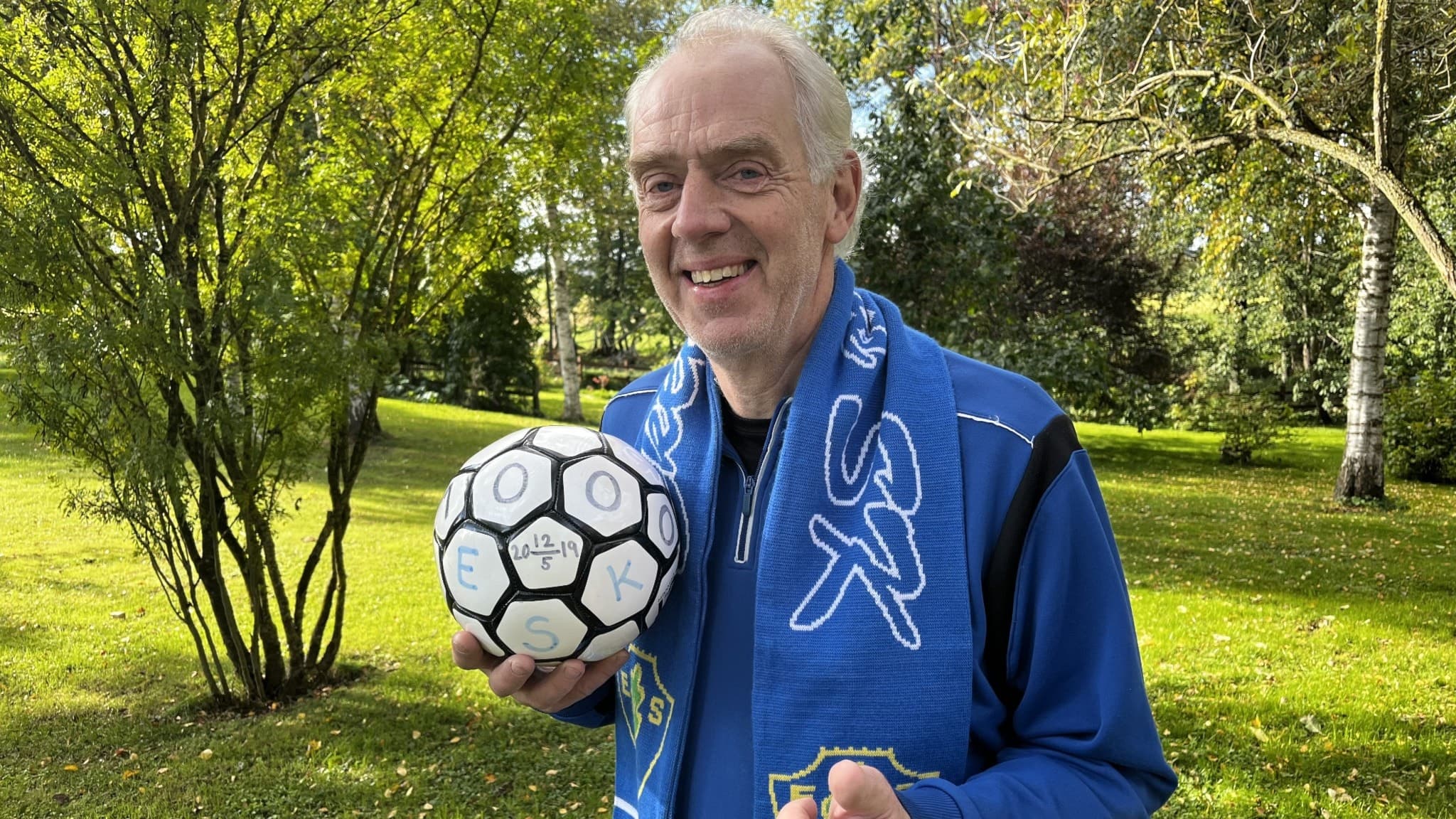 Prästen Mats Löwing, en man med blå träningskläder, håller i en fotboll.