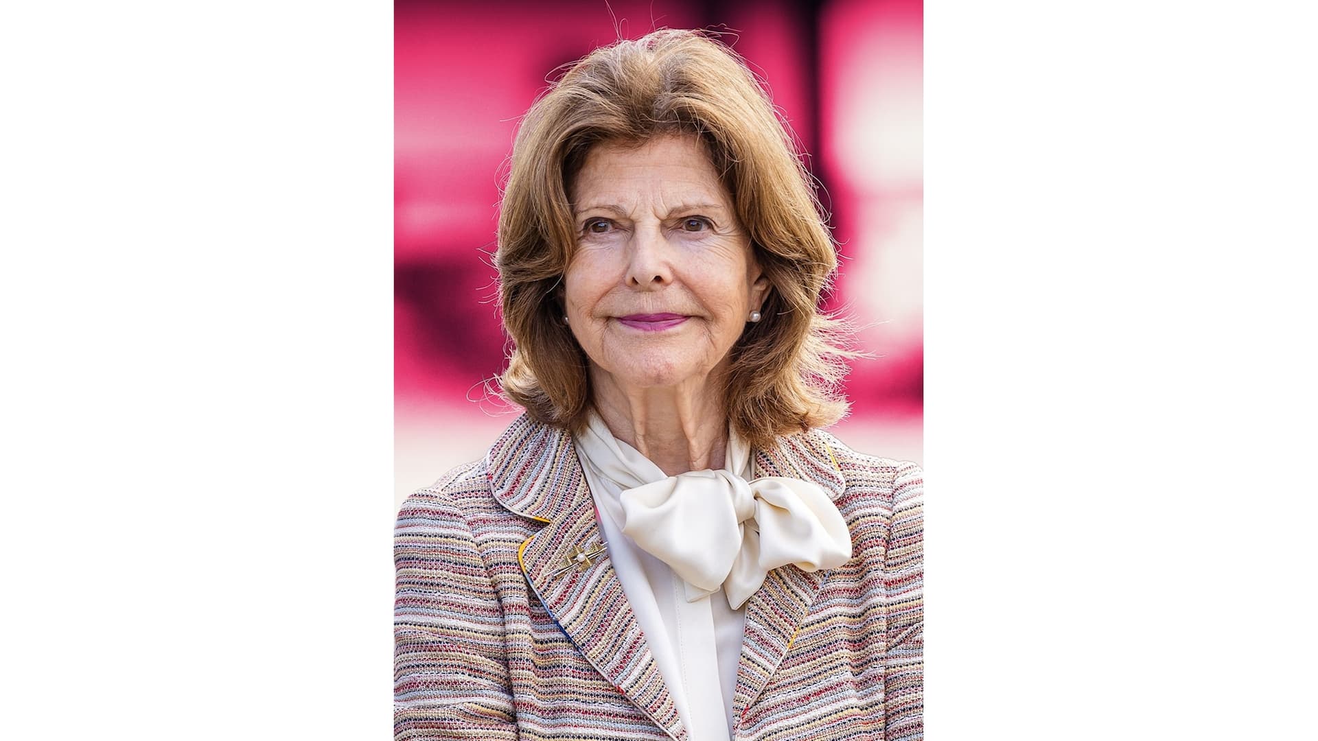 Drottning Silvia mot en rosa barkgrund.