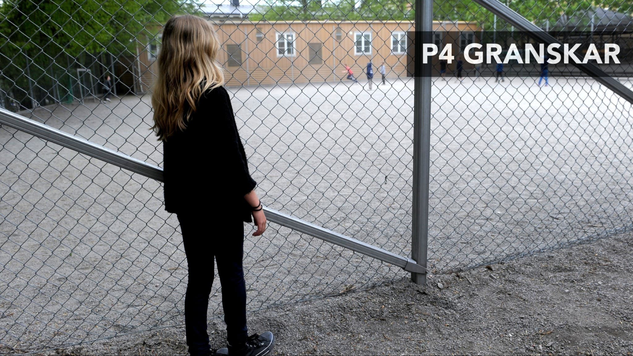 En ensam flicka med långt blont hår står vid ett stängsel och tittar mot en skolgård. Texten 'P4 granskar' är placerad i övre högra hörnet.